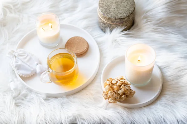 Tasse Kräutertee und brennende Kerze auf rundem weißem Dekortablett — Stockfoto