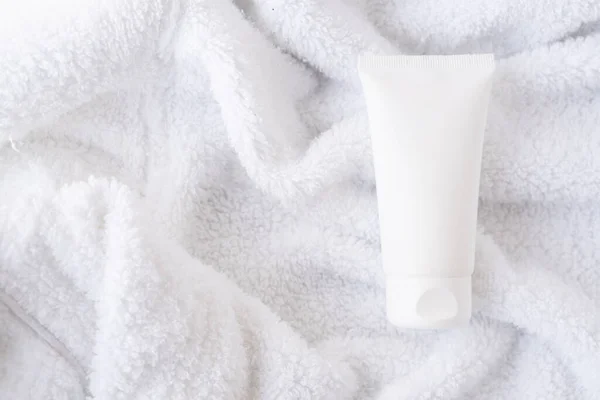 Limpe o tubo de creme cosmético branco no fundo de toalha de algodão branco fofo, mock-up e design pronto — Fotografia de Stock