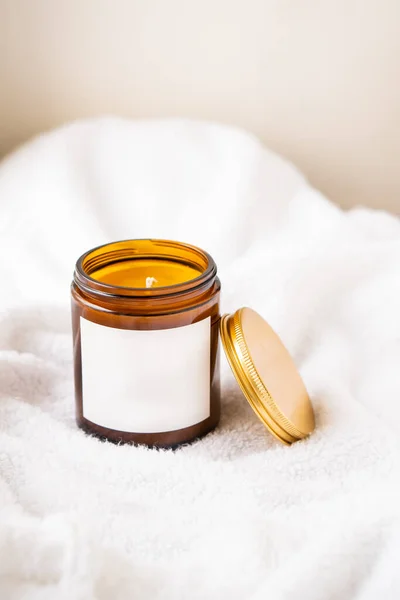 Natural wax candle in brown glass jar with metal lid and white empty clear sticker — Stock Photo, Image