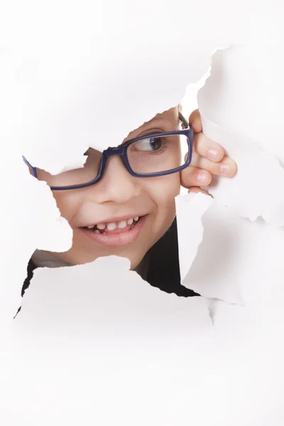 Curious kid looks through a hole in paper — Stock Photo, Image