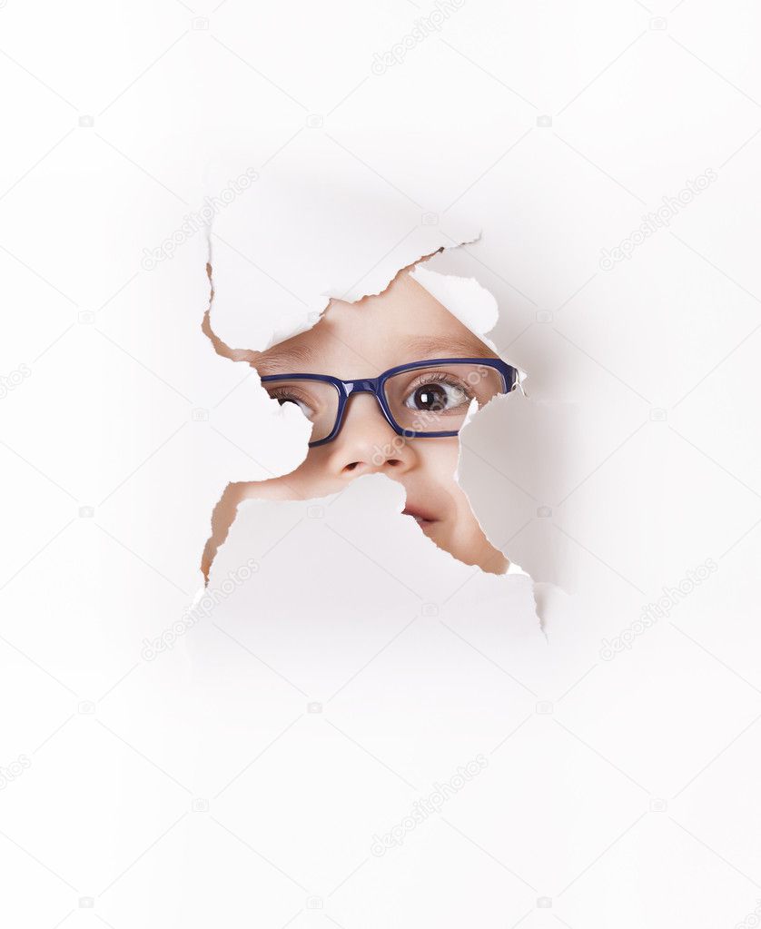 Curious kid looks through a hole in paper