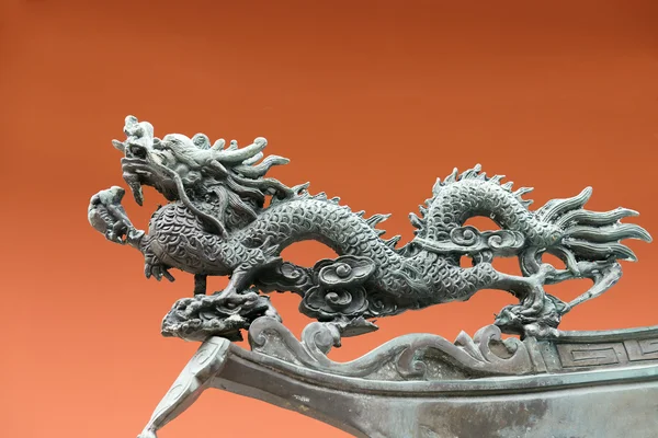 Dragon metal sculpture on orange background — Stock Photo, Image
