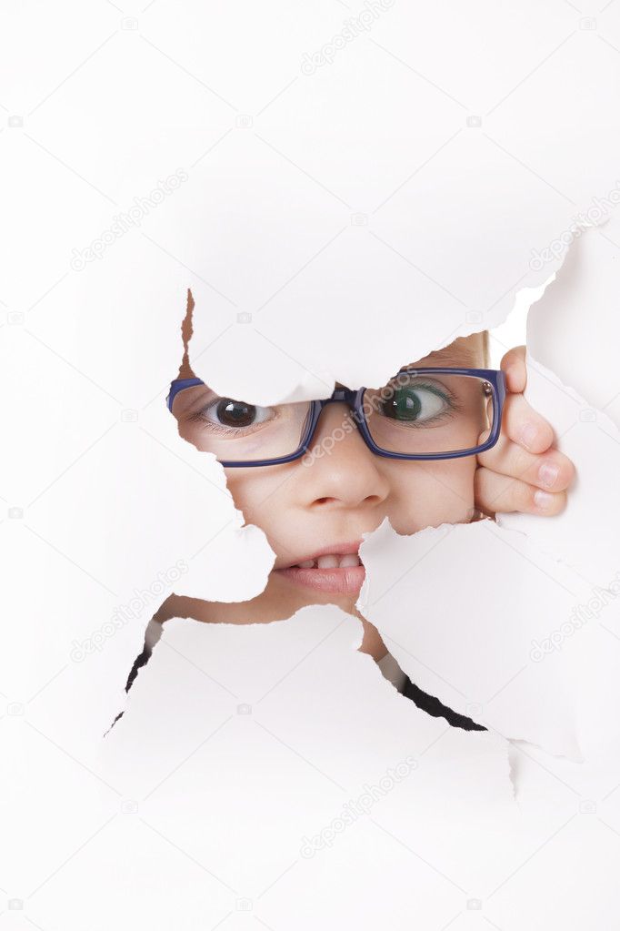 Curious kid looks through a hole in paper