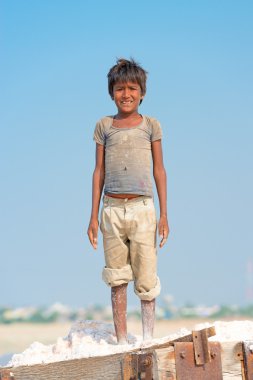 Indian kid on salt farm clipart