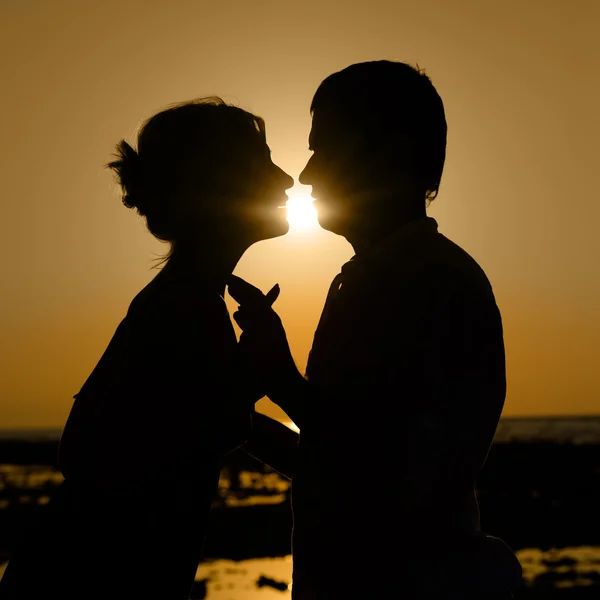 Силуэт целующейся пары на закате — стоковое фото