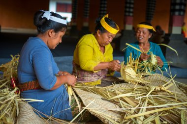Balinese women make baskets for offerings clipart
