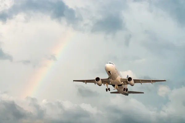 Avión volando en el cielo con arco iris — Foto de Stock