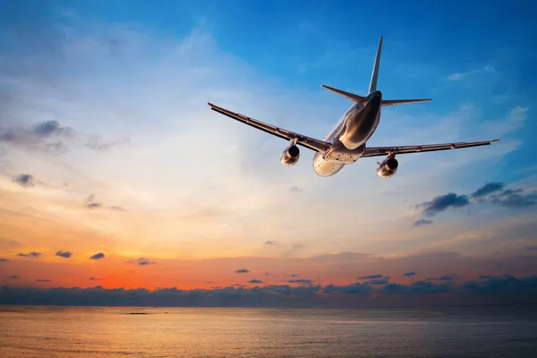 Airplane flying at sunset — Stock Photo, Image