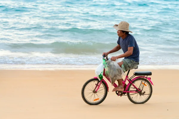 Viejo nativo local ciclismo hombre a lo largo de una playa, Tailandia — Foto de Stock