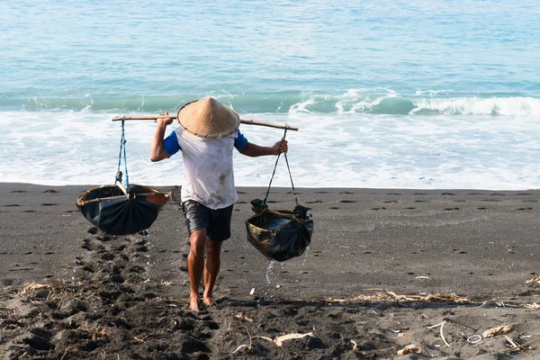 Traditional sea salt production on the volcanic black sand, Bali — Stock Photo, Image