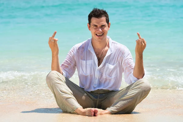 Жест среднего пальца мужчиной на пляже — стоковое фото