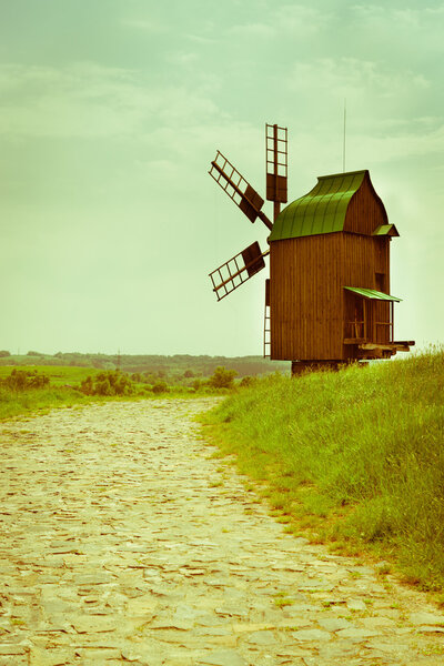 Vintage wooden windmill on stone road