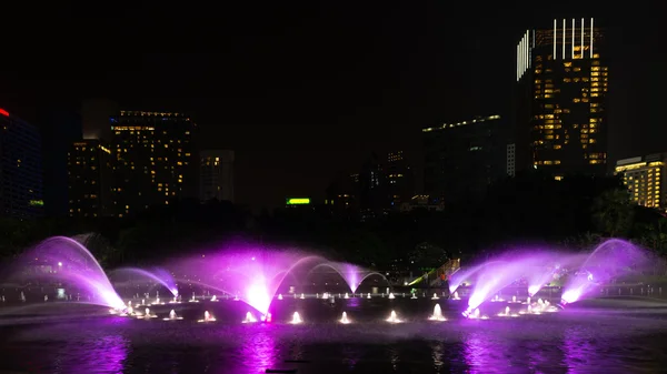 Освещённый фонтан ночью в современном городе — стоковое фото