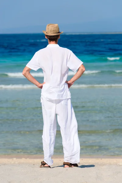 Man in white suit on a tropical beach, back view — Stock Photo, Image