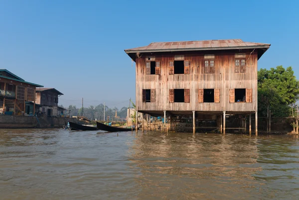 Traditional stilts house and boat in water under blue sky — Stock Photo, Image