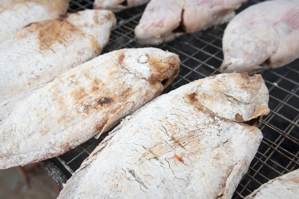 Grilling fish in salt on campfire — Stock Photo, Image