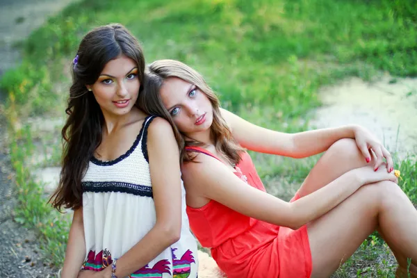 Dos mujeres jóvenes en vestidos sentados juntos — Foto de Stock