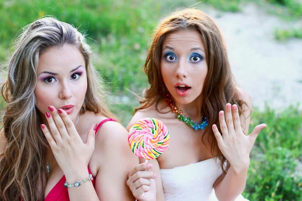 Two pretty caucasian girls with lollipop surprised — Stock Photo, Image