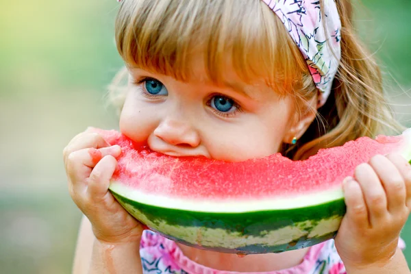 Adorable little girl eats a slice of watermelon outdoors — Stock Photo, Image