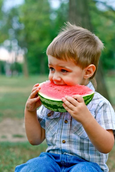 Caucasian little boy eats a slice of watermelon — Stock Photo, Image