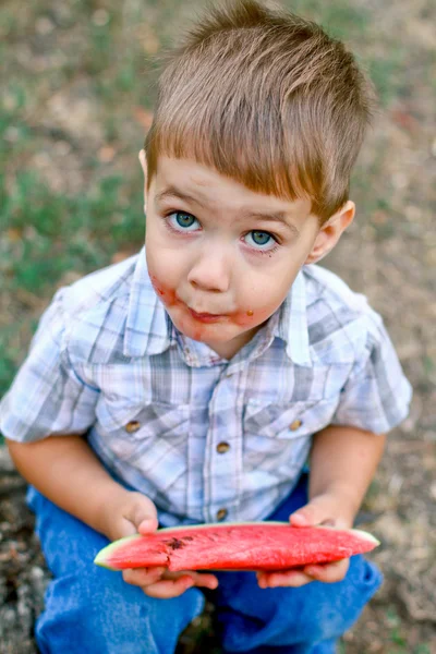 Caucasian little boy eats a slice of watermelon — Stock Photo, Image