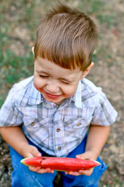 Caucasian little boy eats a slice of watermelon — Stock Photo, Image