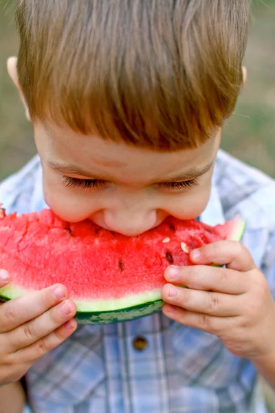 Caucasian little boy eats a slice of watermelon — Stock Photo, Image