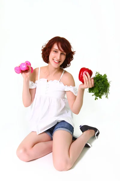 Jeune femme avec haltères et légumes — Photo