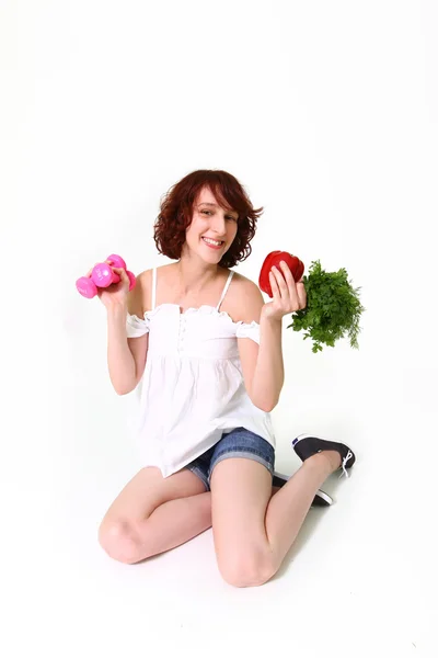 Jeune femme avec haltères et légumes — Photo