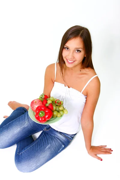 Ung kvinna med frukt och grönsaker på en maträtt — Stockfoto