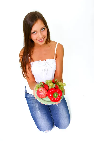 Ung kvinna med frukt och grönsaker på en maträtt — Stockfoto