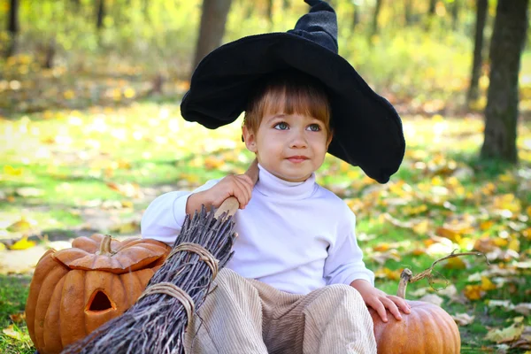 Portrait of a little boy with halloween pumpkins, a broom and a — Stock Photo, Image