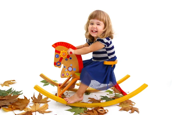 Portrait of a smiling little girl on a wooden horse isolated on — Stock Photo, Image