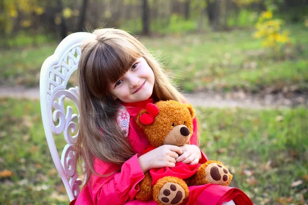 Niña con un osito de peluche en el bosque de otoño — Foto de Stock