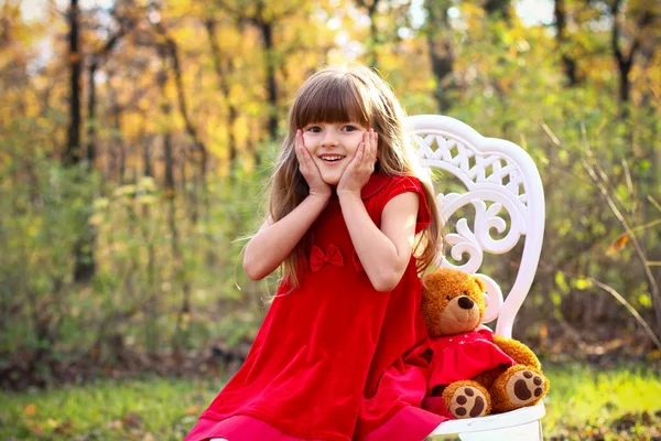 Enthusiastic little girl with a teddy bear in the autumn forest — Stock Photo, Image