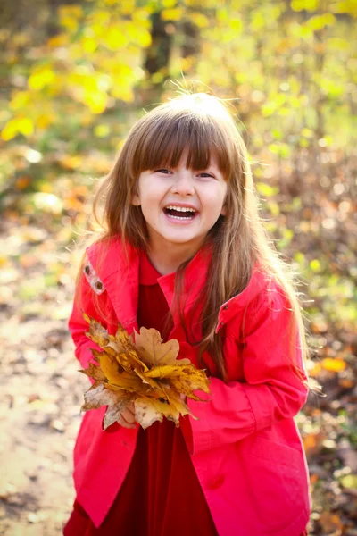 Портрет смеющейся девушки в осеннем лесу с кленовым листом — стоковое фото