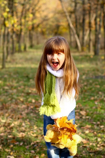 Kleines Mädchen schreit im herbstlichen Wald und hält Blätter — Stockfoto