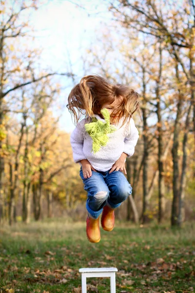 Little girl jumping from a chair outdoors — Stock Photo, Image