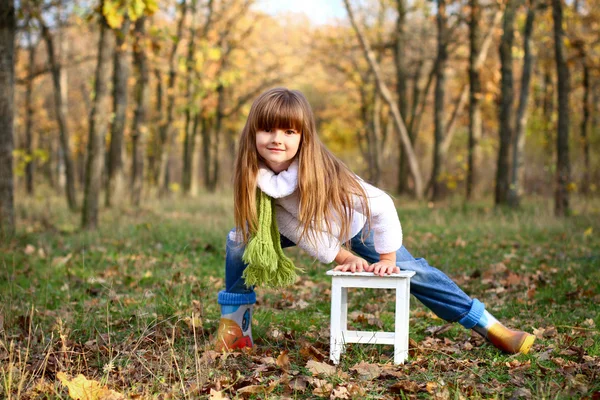 Little girl standing near white chair outdoors — Stock Photo, Image