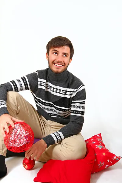 Jovem sentado com almofadas de Natal isolado em backg branco — Fotografia de Stock