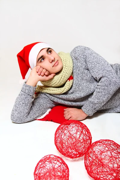 Jovem com um cachecol, chapéu Papai Noel e bolas vermelhas isoladas o — Fotografia de Stock