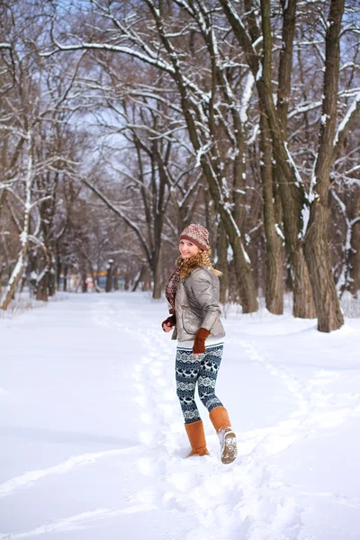 Leende flicka kör genom snön i en winter park utomhus — Stockfoto