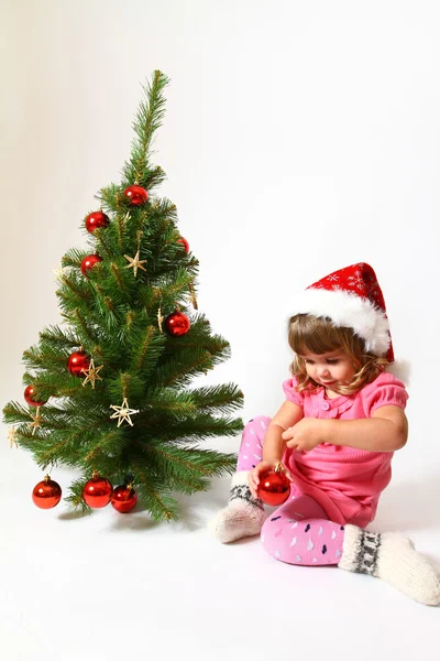 Sweet baby in a hat of Santa Claus sitting near New Year or Chri — Stock Photo, Image