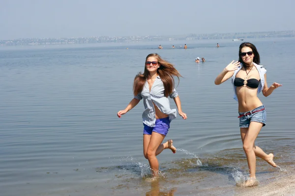 Šťastné mladé ženy běh přes pláž — Stock fotografie