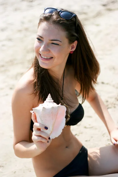 Gelukkig jonge vrouw spelen met shelll op het strand — Stockfoto