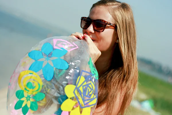 Gelukkig jonge vrouw opblazen van de opblaasbare bal — Stockfoto