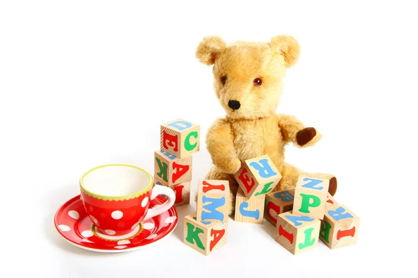 Teddy bear, cup, plate and box of bricks isolated on white — Stock Photo, Image