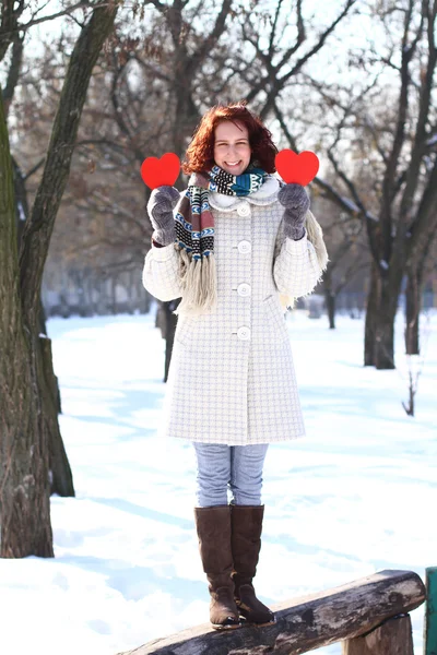 Happy winter girl with two red hearts standing on bench — Stock Photo, Image