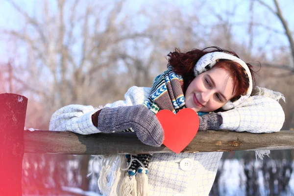 Dreaming winter girl holding red heart outdoors — Stock Photo, Image