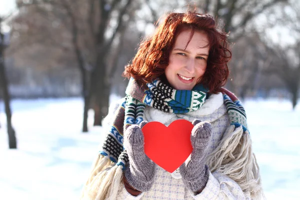 Romantic girl holding a red heart on the background of a winter — Stock Photo, Image